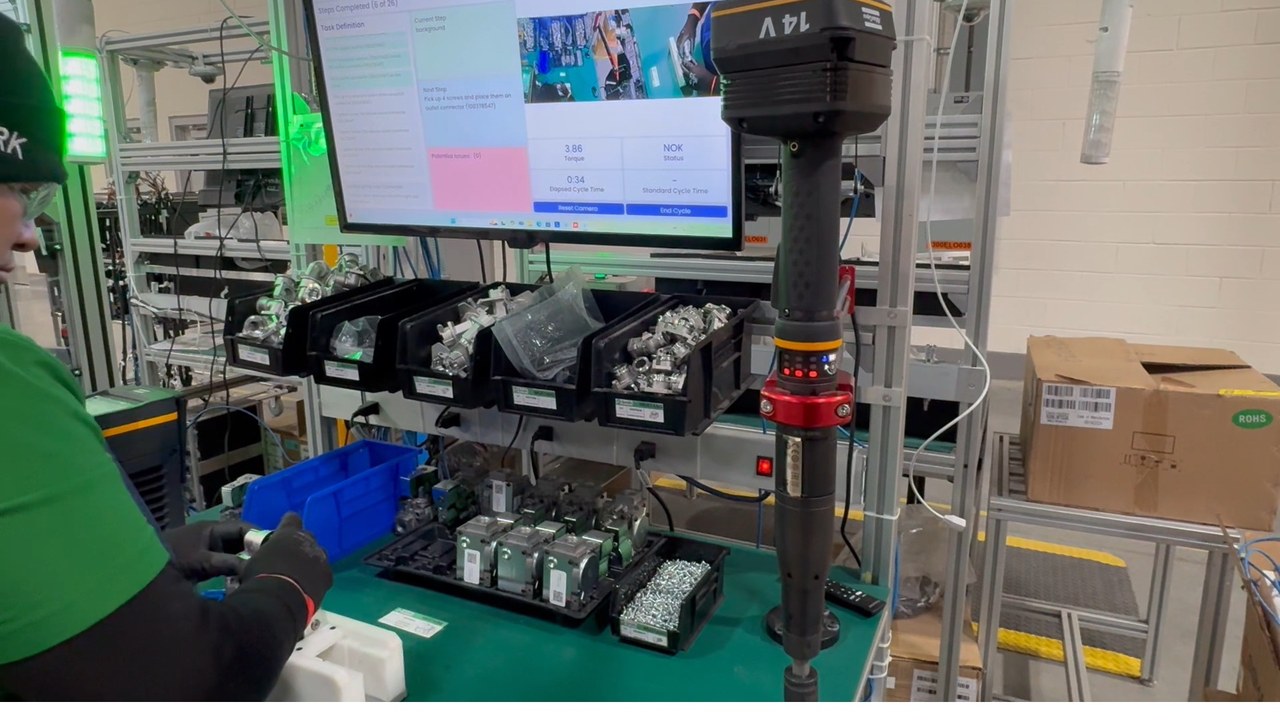 Assembly Copilot in a real factory deployment: operator at a workstation while the monitor shows the product UI with step guidance, elapsed cycle time, and live torque reading.